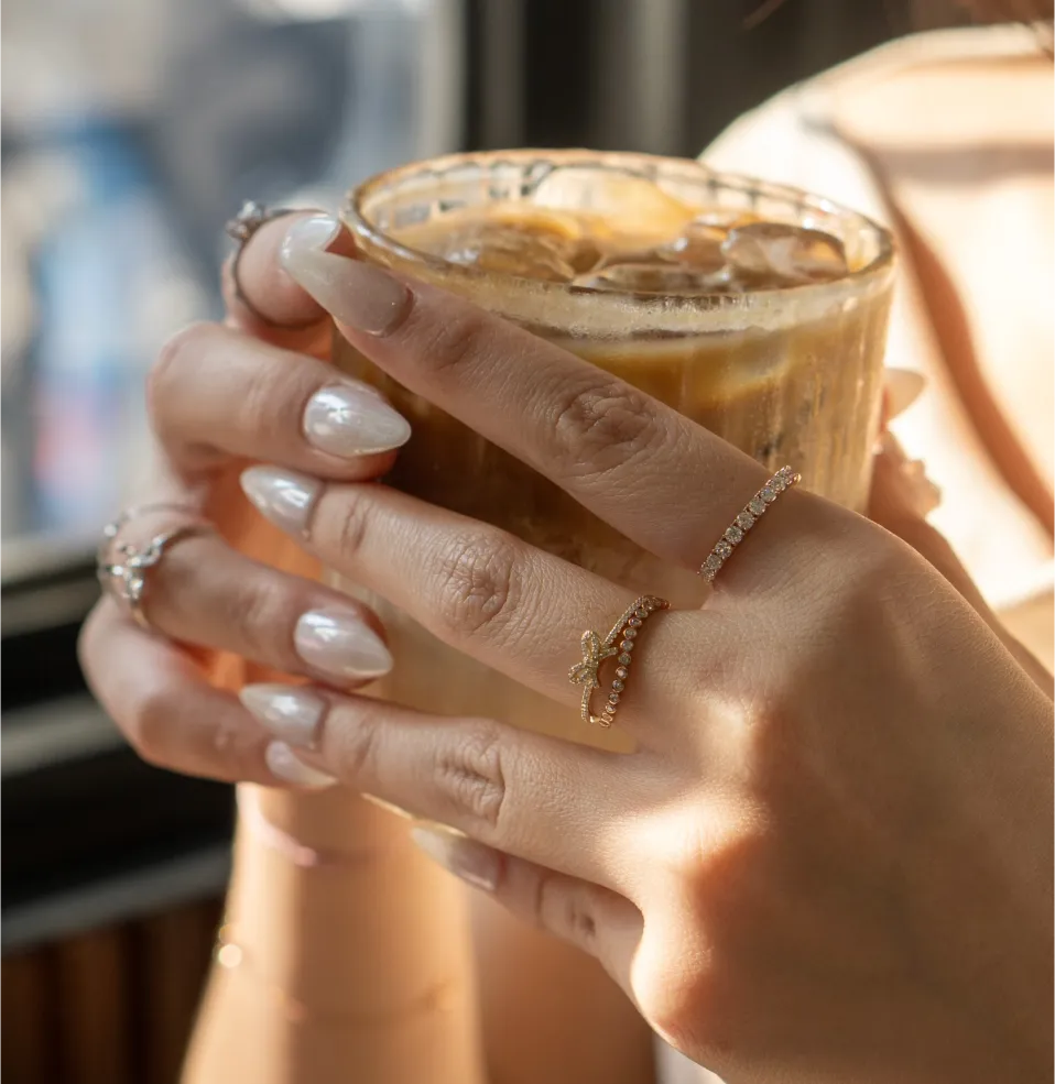 comm-4 A group of diverse hands stacked together, some with nail polish and one hand with a ring and a tattoo.