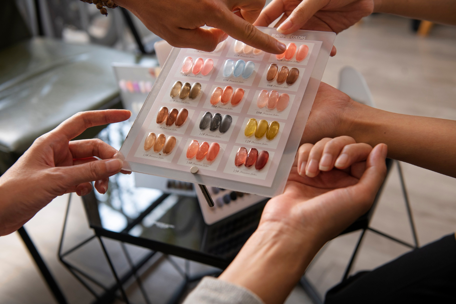 2149975490 Hands selecting nail polish colors from a display of various artificial nail samples in a salon.